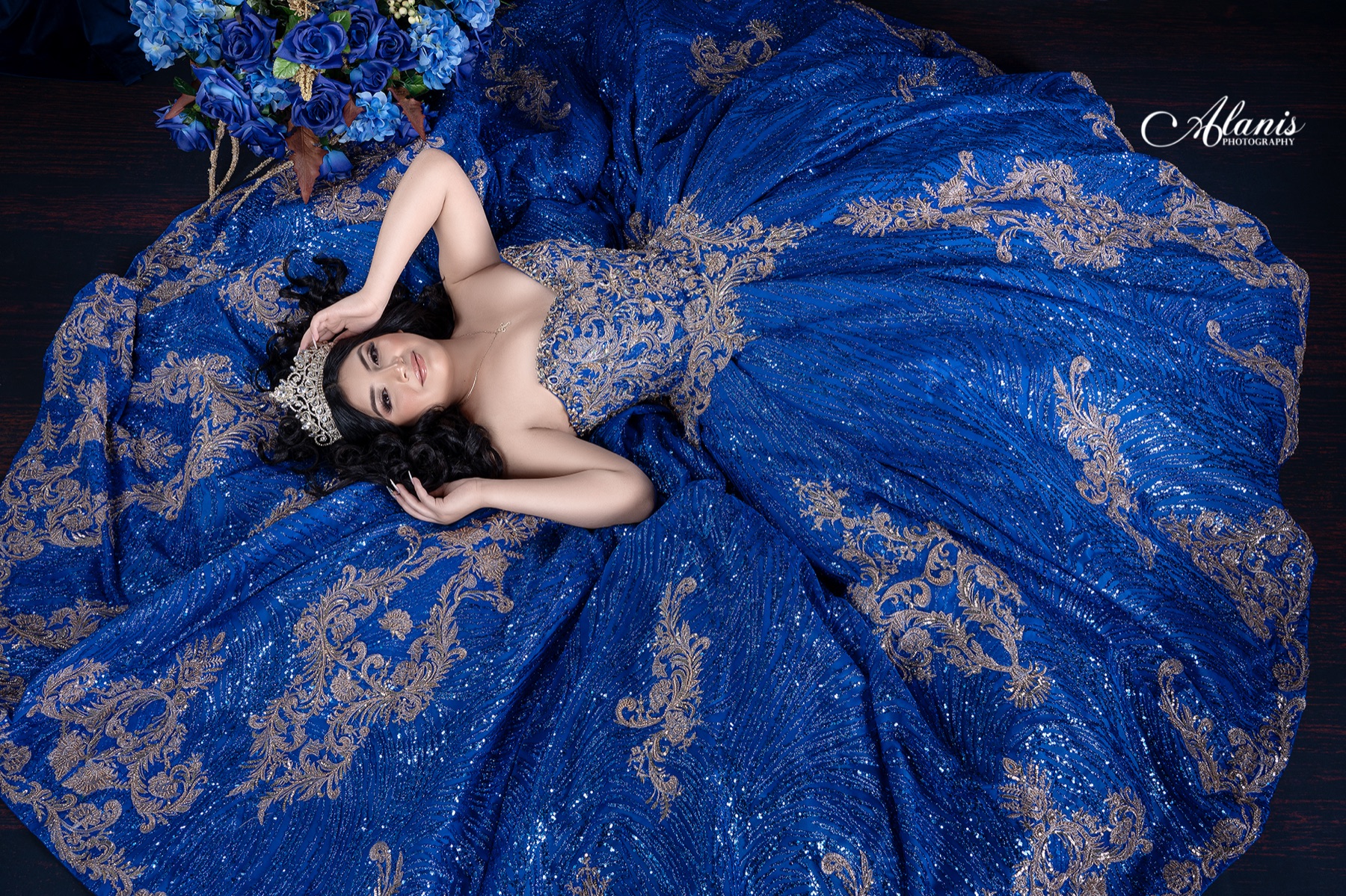 Quinceañera surrounded by the sweeping train of a royal blue gown