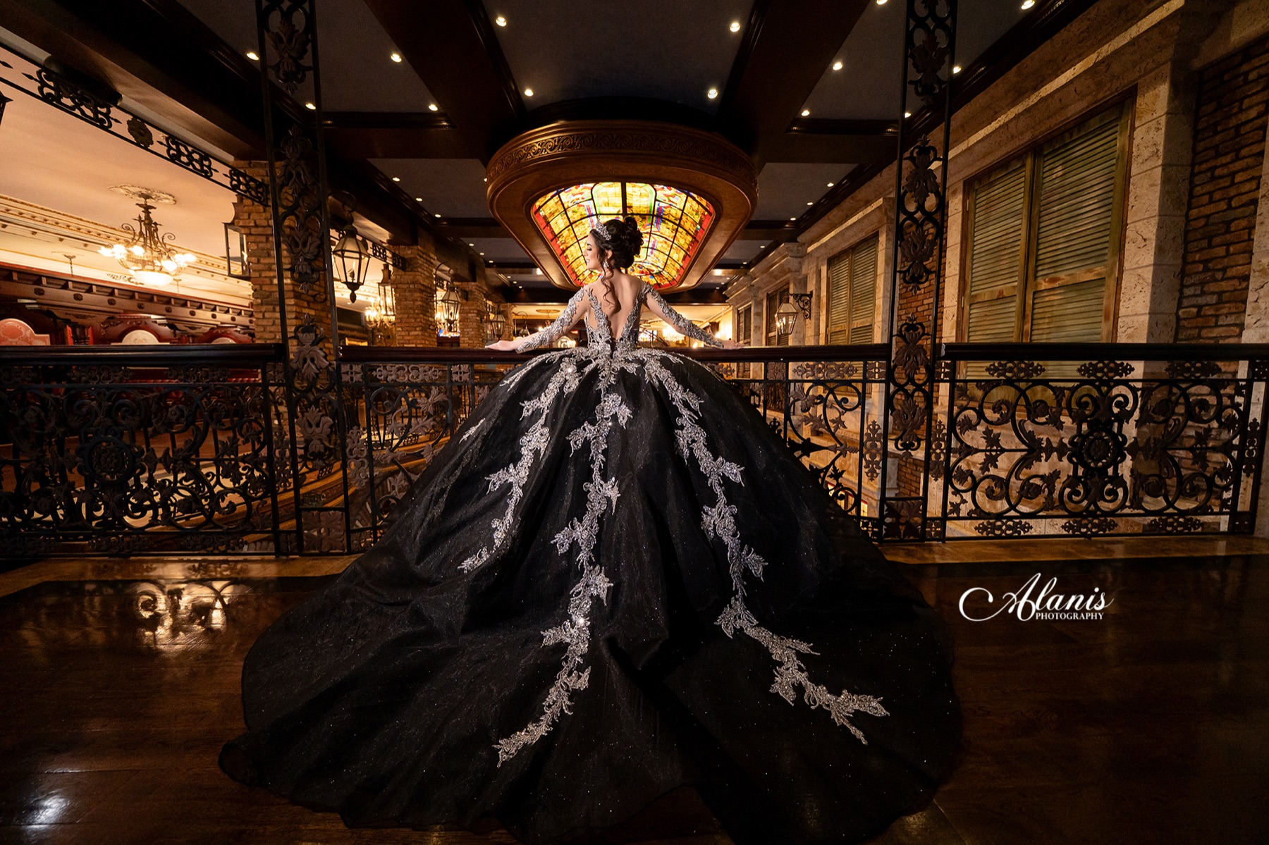 Quinceañera in a black and silver gown in an ornate interior
