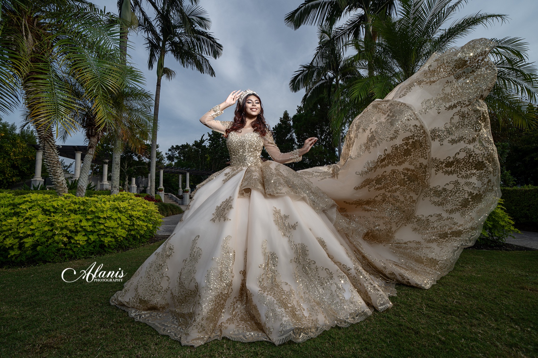 Quinceañera lifting the embroidered train of a champagne gown