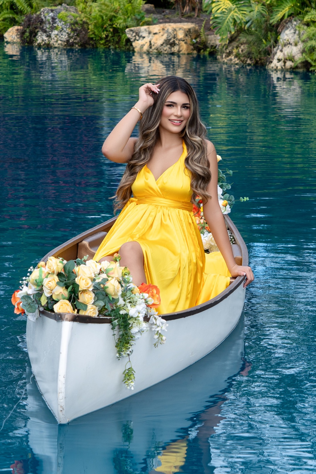 Quinceañera in a yellow dress aboard a flower-filled boat