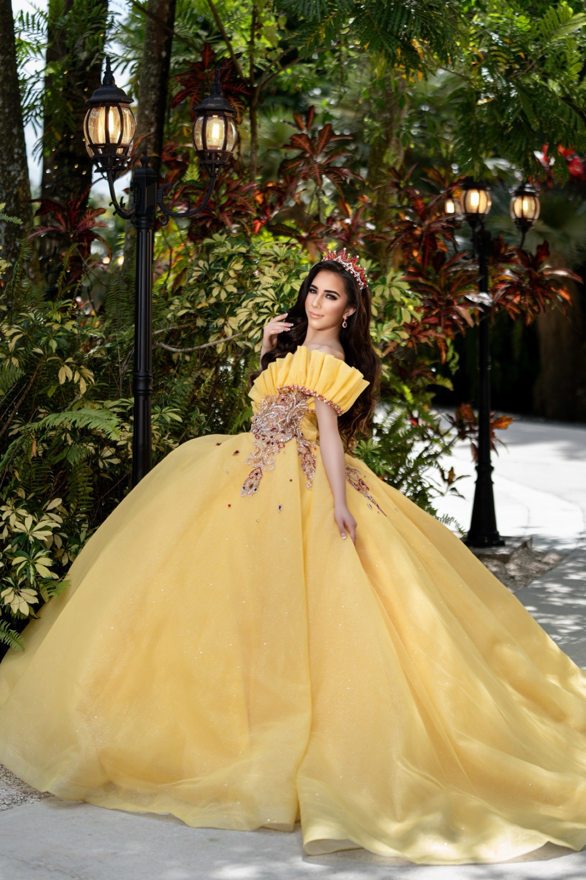 Quinceañera in a yellow gown in a tropical garden