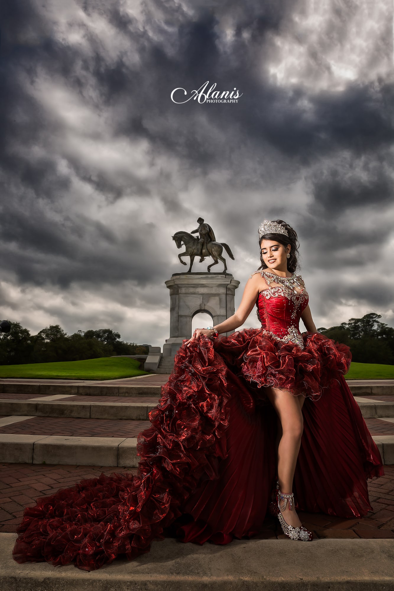 Quinceañera in a dramatic red and black gown beneath a stormy sky