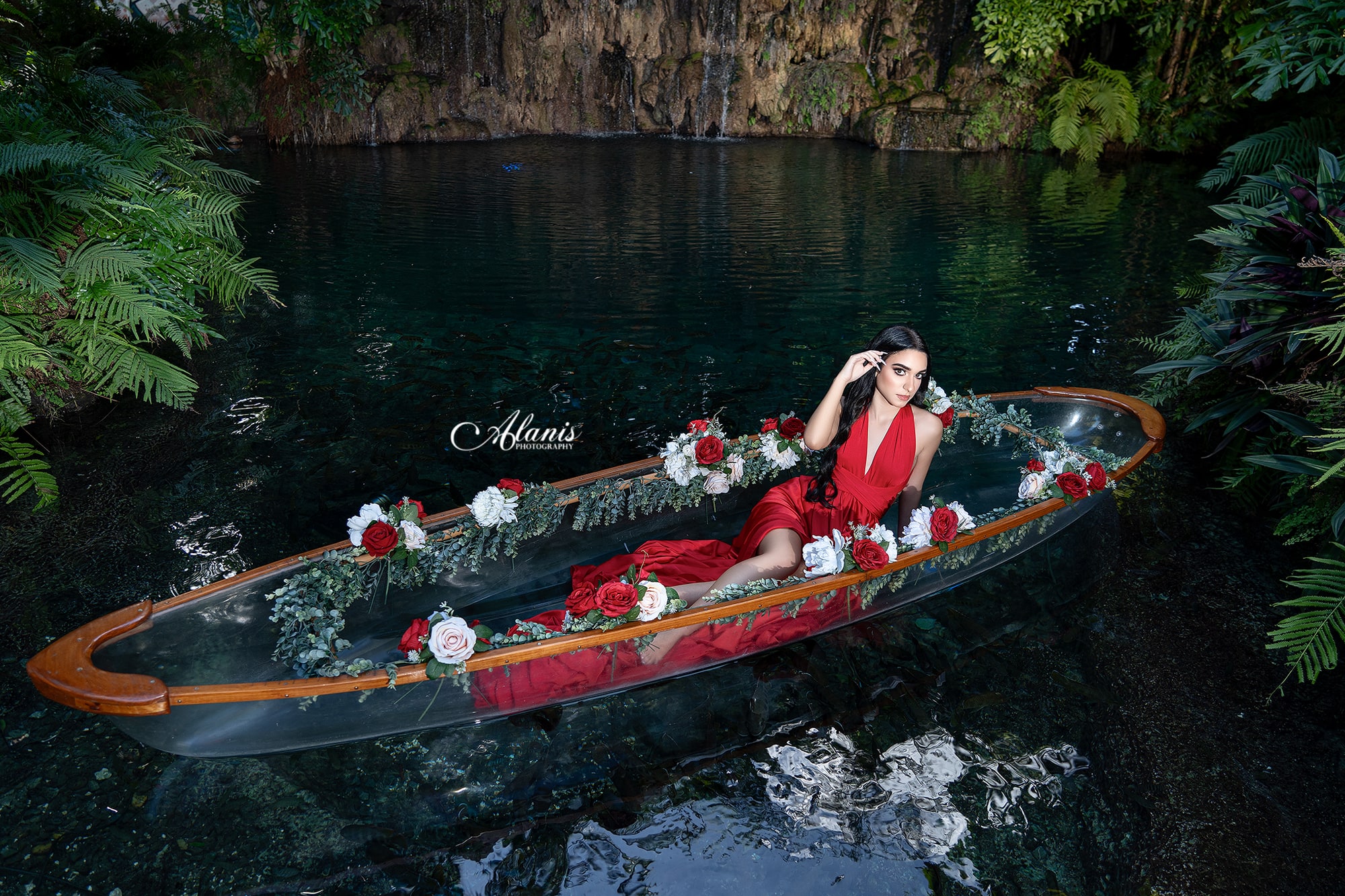 Quinceañera in a red gown aboard a flower-filled boat