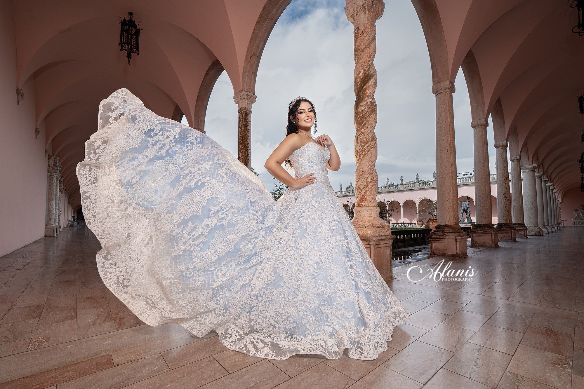 Quinceañera in a white gown beneath architectural arches