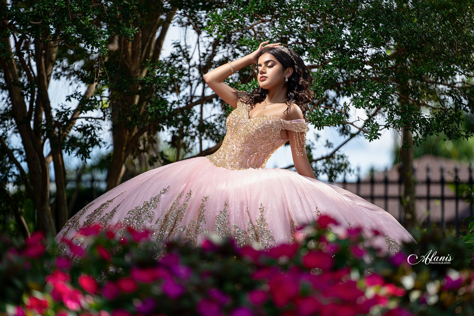 Quinceañera in a pink gown in a flower garden