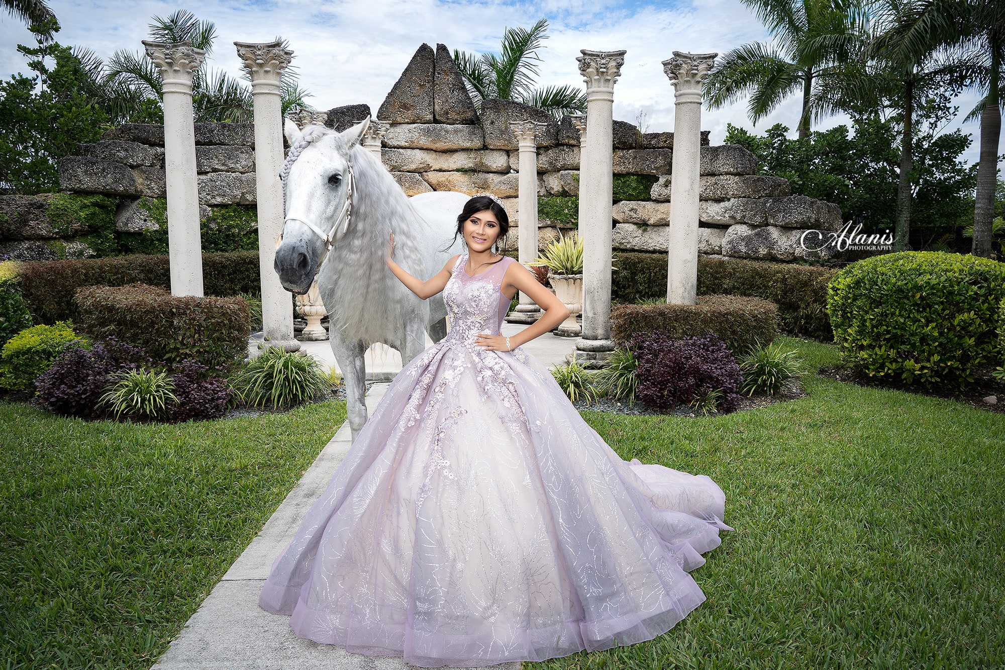Quinceañera in a silver gown in a formal garden