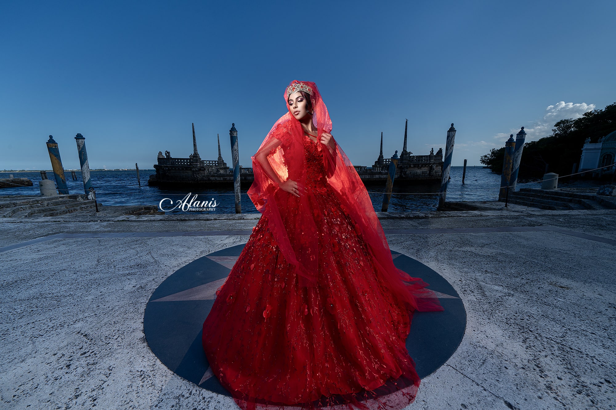 Quinceañera in a red gown at a seaside landmark