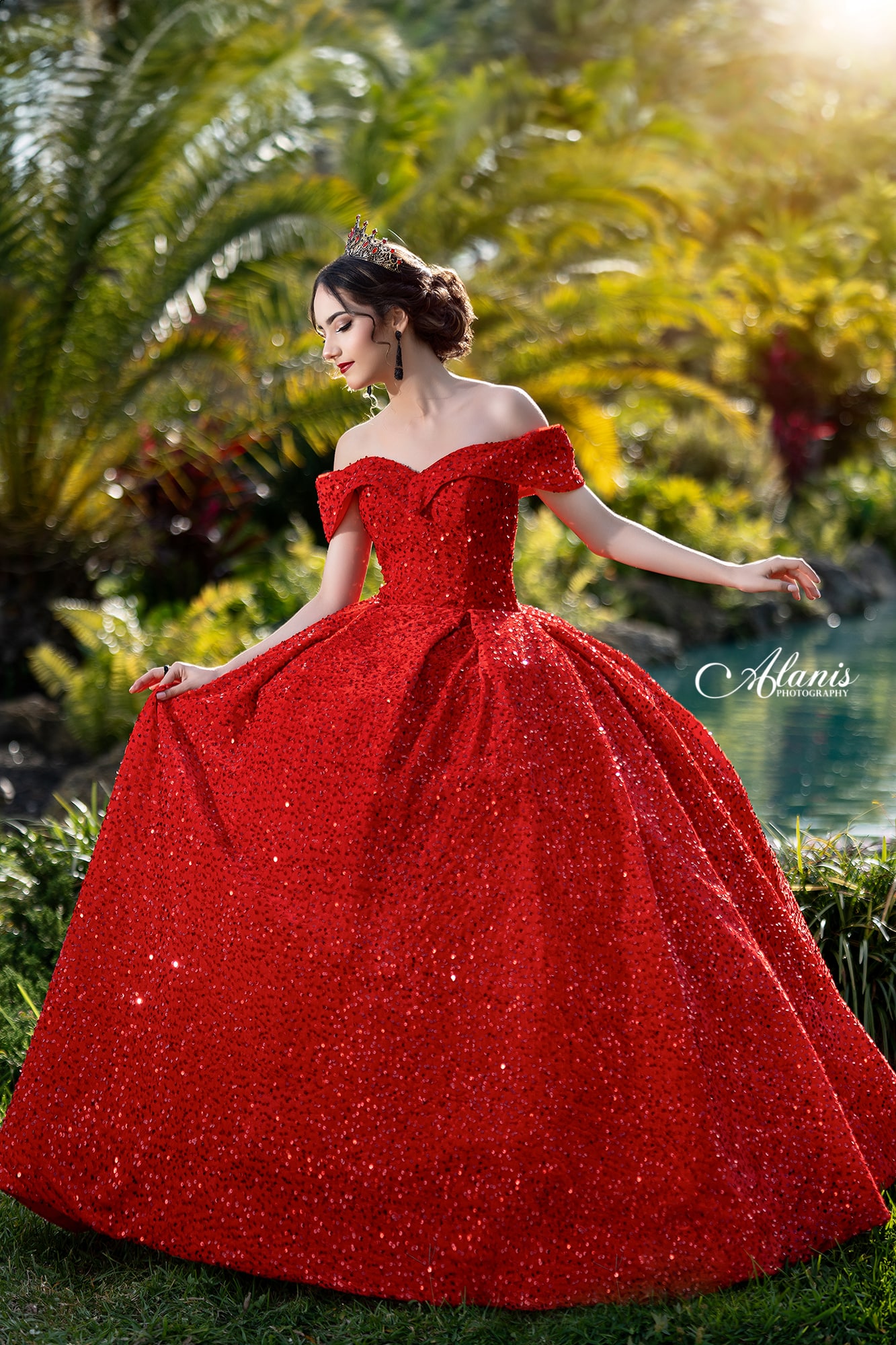 Quinceañera in a red gown in a tropical garden