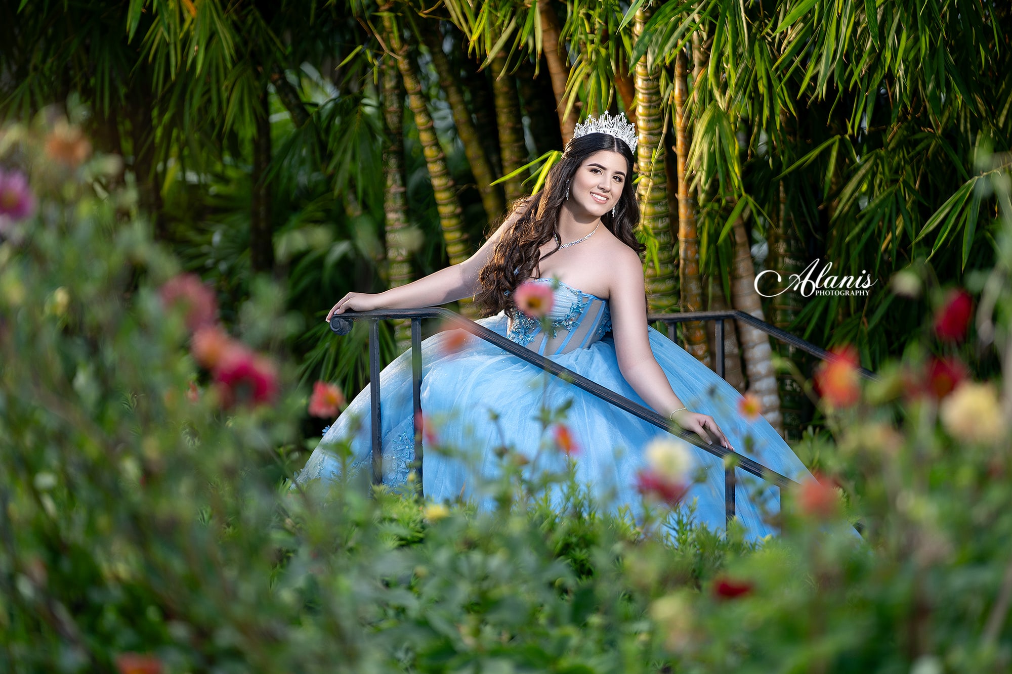 Blue quinceañera portrait framed by garden flowers