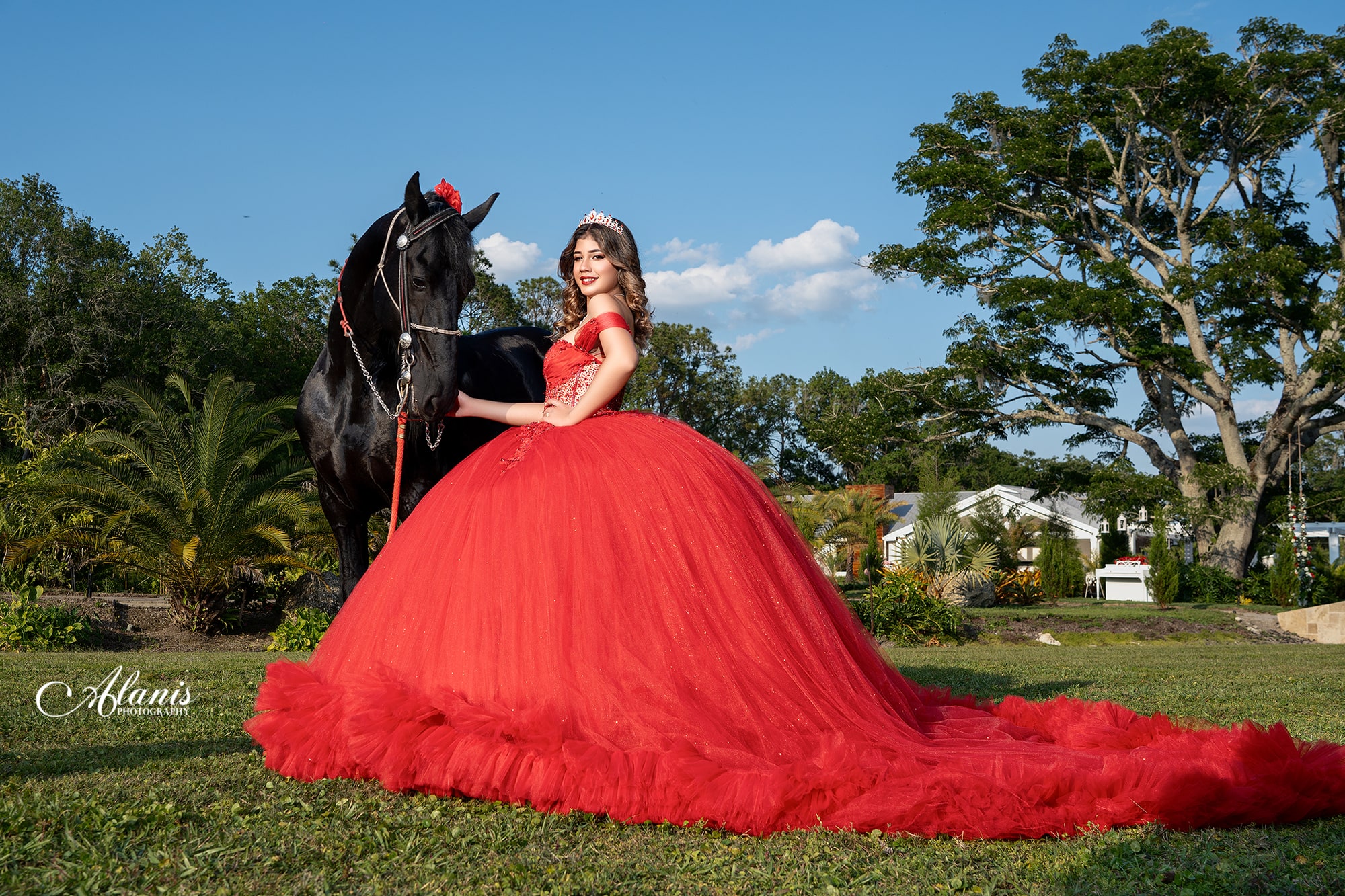 Quinceañera in a red gown beside a black horse