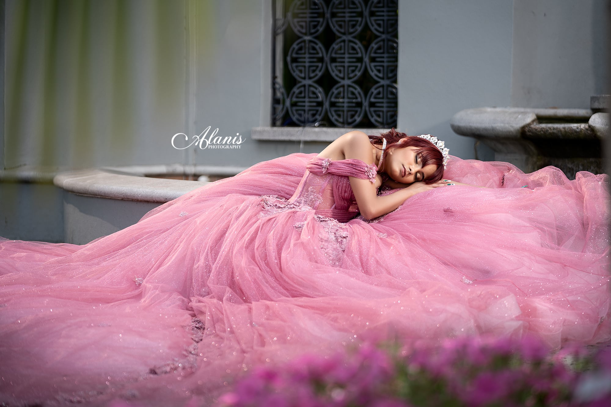 Quinceañera reclining in a pink gown on a studio set