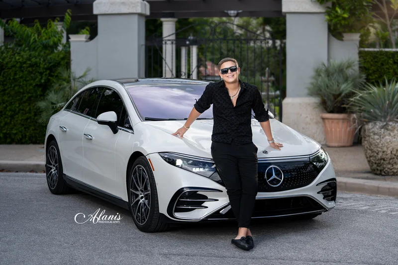 XV for Him portrait in a black outfit beside a white car