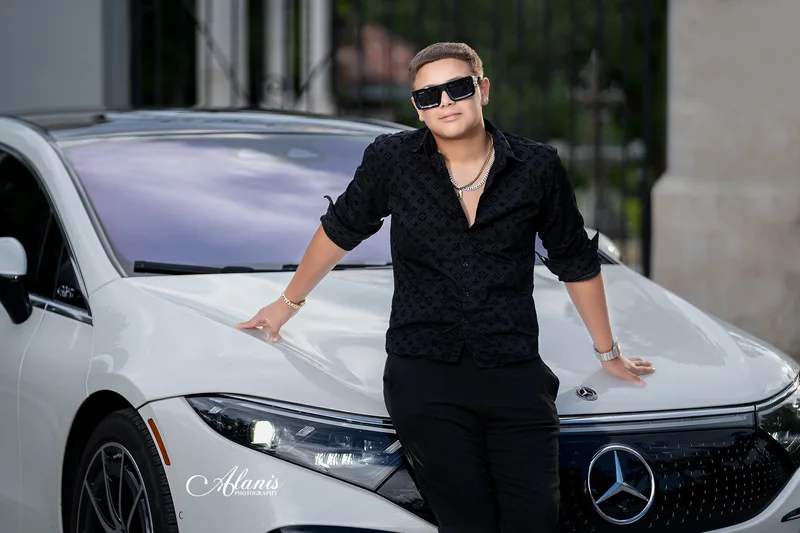 XV for Him portrait in a black outfit beside a white car