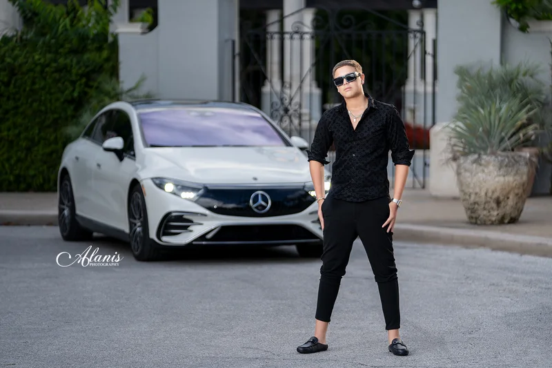 XV for Him portrait in a black outfit beside a white car