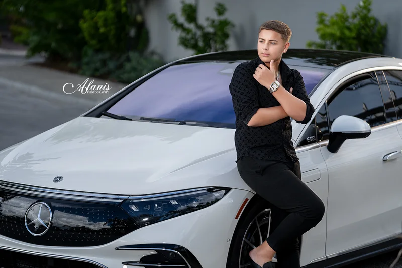 XV for Him portrait in a black outfit beside a white car