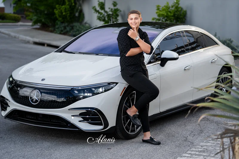 XV for Him portrait in a black outfit beside a white car