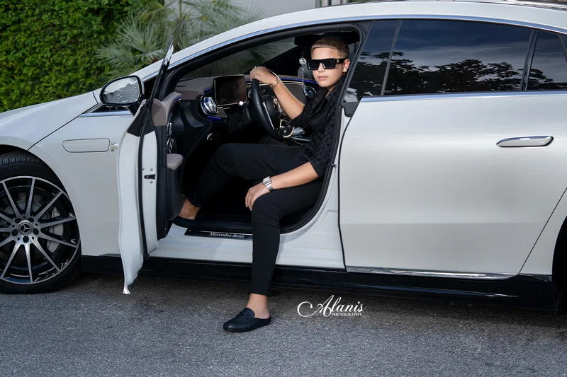 XV for Him portrait in a black outfit beside a white car